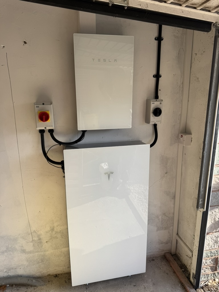 Tesla battery and wall-mounted equipment inside a garage with electrical isolators